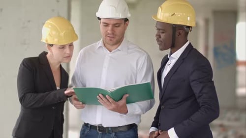 Group of Smiling Builders in Hardhats with Clipboard and Blueprint Outdoors