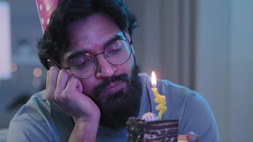 Man with Birthday Cake and Candle Looks Bored