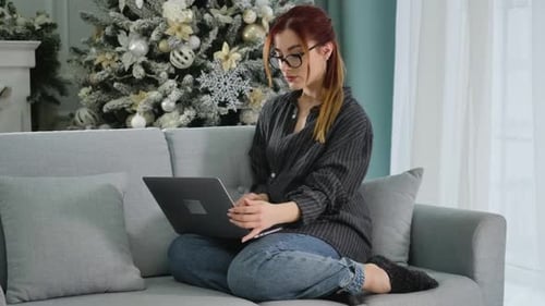 Wide Shot Portrait of Tired Confident Woman Closing Laptop with Christmas Tree at the Background
