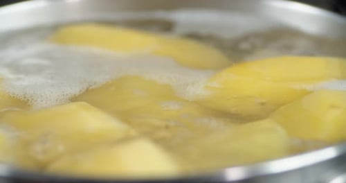 In Wasser gekochte Kartoffeln in einem Topf mit Luftblasen.