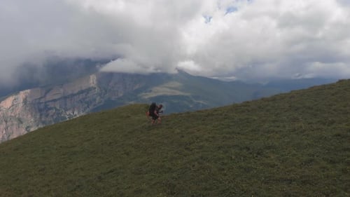 Drone Shot of a Tourist with a Backpack Up the Hill