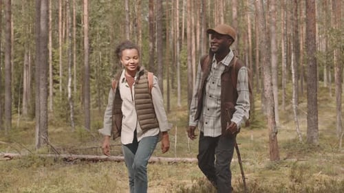 African-American Couple with Backpacks Hiking in Forest