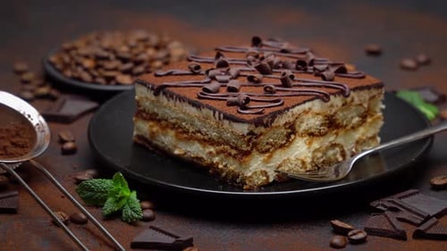 Portion of Traditional Italian Tiramisu dessert and pieces of chocolate bar