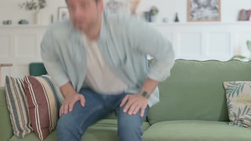 Man Stands Up and Walks Away From Couch