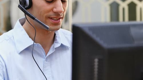 Lächelnder Kundendienstleiter spricht am Schreibtisch 4k über Headset