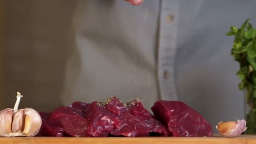 Chef Seasoning Raw Meat with Fresh Herbs