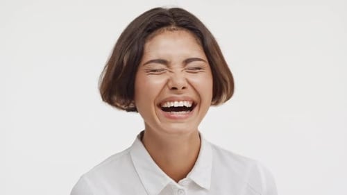 Young Beautiful Brunette East Asian Female in Shirt Laughing on White Background in Slowmotion