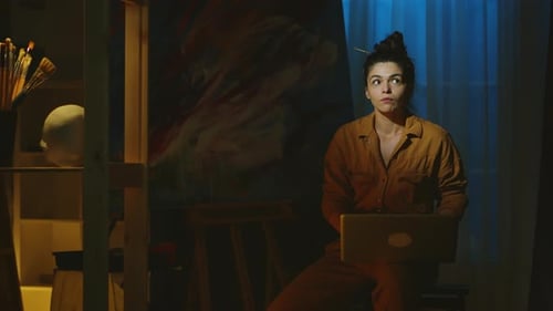 Woman Artist Uses Laptop in Dimly Lit Studio