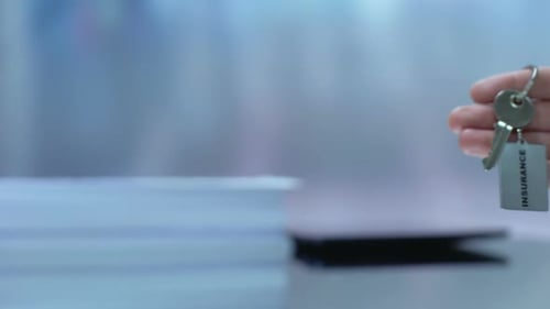 Hand Holding Keys with Insurance Tag, Close Up