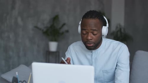 Young Adult Working on Laptop with Headphones at Home