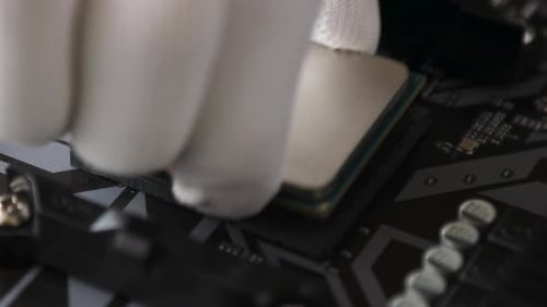 A technical specialist's hand in white gloves installs the CPU from socket on the motherboard