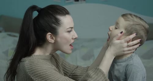 Woman Opens Mouth While Examining Boy's Throat