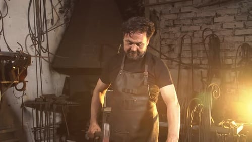 Blacksmith Hammering Metal in a Workshop