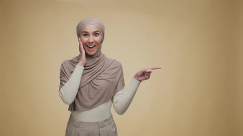 Woman Wearing Headscarf Points to the Side