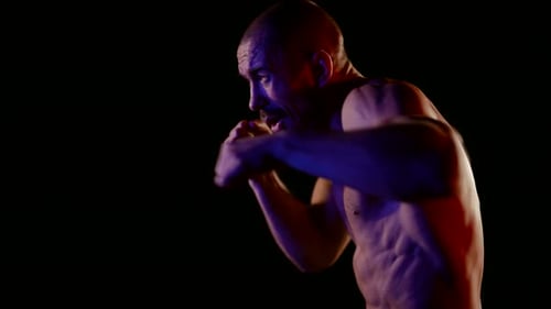 Intense Bare-chested Man Boxing in Dramatic Lighting