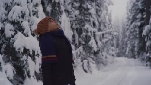 Boy watching trees on snowy day.