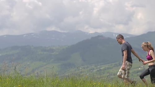 Couple Hiking Together in Grassy Mountain Field