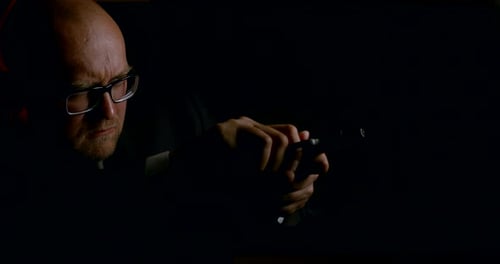 Dangerous Male Killer Is Reloading Gun and Aiming Around in Dark Room