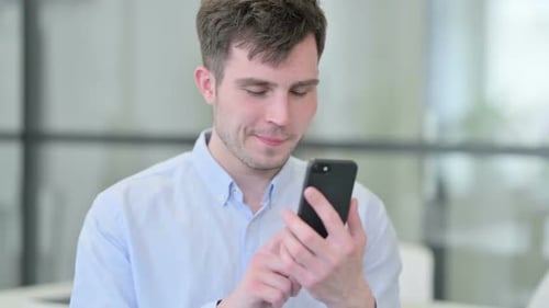 Young Adult Using Smartphone in Modern Office