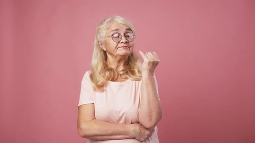Senior Lady in Glasses Deciding Solution Counting on Fingers From One to Five Pink Studio Background