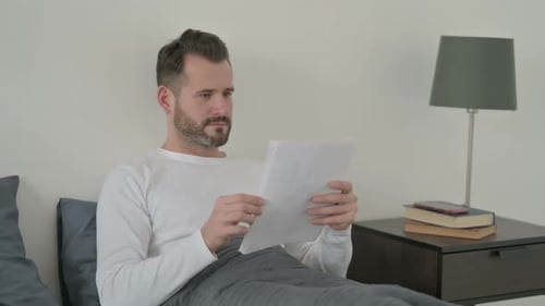 Man in Bed Reads Good News and Celebrates