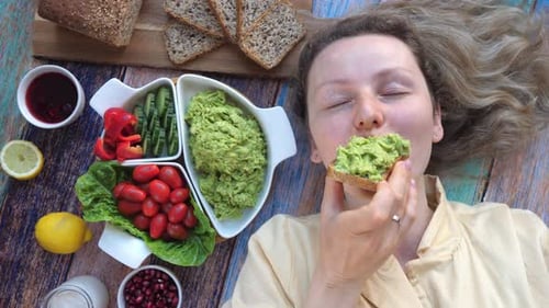 Young Smiling Woman Eating Avocado Toast At Home.