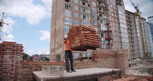 Building a House a Crane Filed for a Working Pallet of Bricks