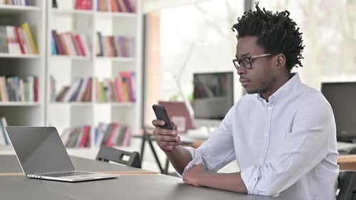 Young Adult Using Phone While Working at Desk