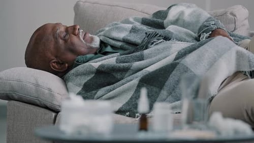 Senior Man Resting at Home Under Blanket