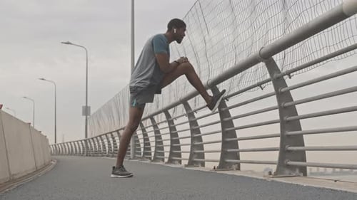 Man Stretching on Bridge Before Exercising