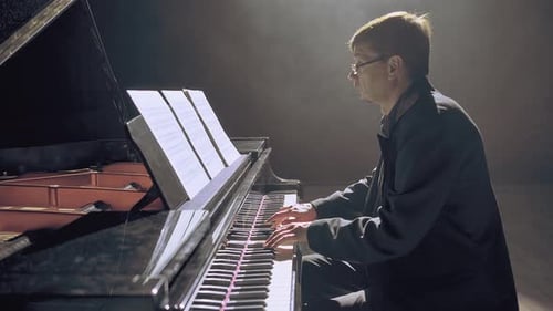 Man Plays Grand Piano in Dimly Lit Room