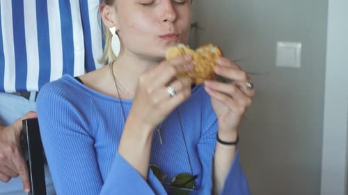 Young Woman Eating a Pastry Indoors in Daylight