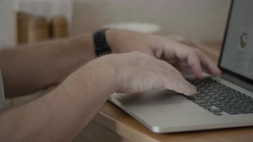Senior Adult Typing on Laptop Computer at Home