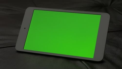 Silver tablet with green screen display indoor on couch exposed 4K 2160p 30fps UltraHD footage - Bl