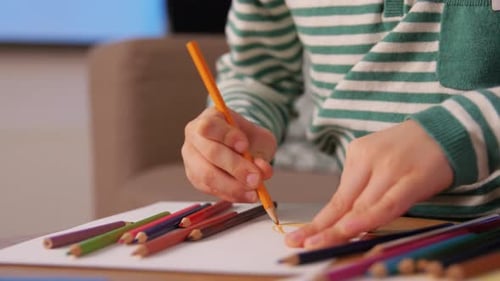 Focused Child Drawing with Colored Pencils at Home