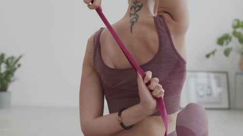 Woman Stretching with Pink Yoga Strap Indoors