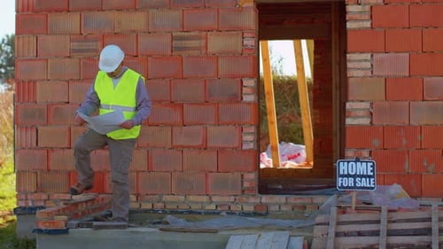 Worker Builder Designer Architect Analyzes Blueprints on Construction Site of House Real Estate
