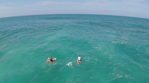 Aerial view of two men sitting on their boards while sup stand-up paddleboard surfing in Hawaii