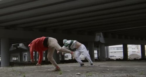 Acrobatic Athletic Young Adults Performing Flips Under Bridge