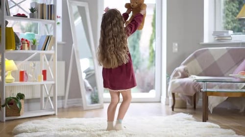 Girl Dances with Teddy Bear in Living Room