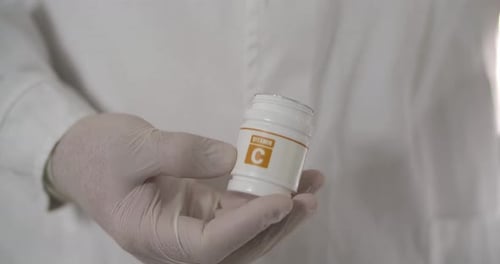 Gloved Hand Opening Vitamin C Bottle, Pills