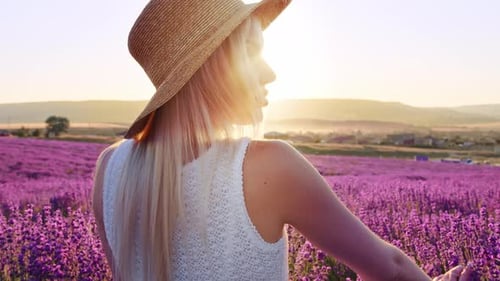 Portrait d'une femme blonde avec un chapeau dans les champs de lavande en été