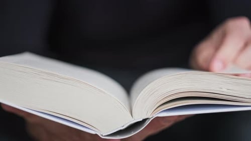 Young Man Reading a Book and Turning Pages Close Up Slow Motion