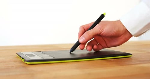 Hand Using Stylus on Digital Tablet on Desk