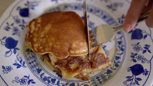 Cutting Pancakes on Plate with Knife and Fork