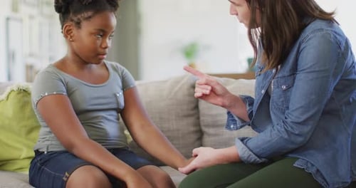 Caucasian woman arguing with her african american daughter in living room