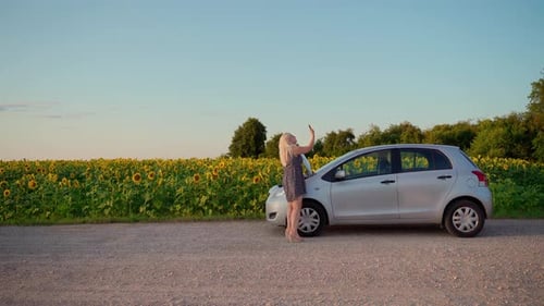 Woman call for help by phone on road at car. Young adult female 30s has problem with cellular signal