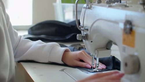 Hands Sewing Black Fabric with Sewing Machine