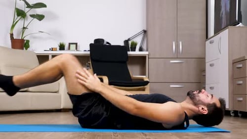 Man Does Yoga and Stretches Indoors at Home