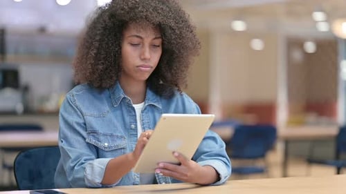 Excited Young Latin Woman Celebrating Success on Tablet in Cafe